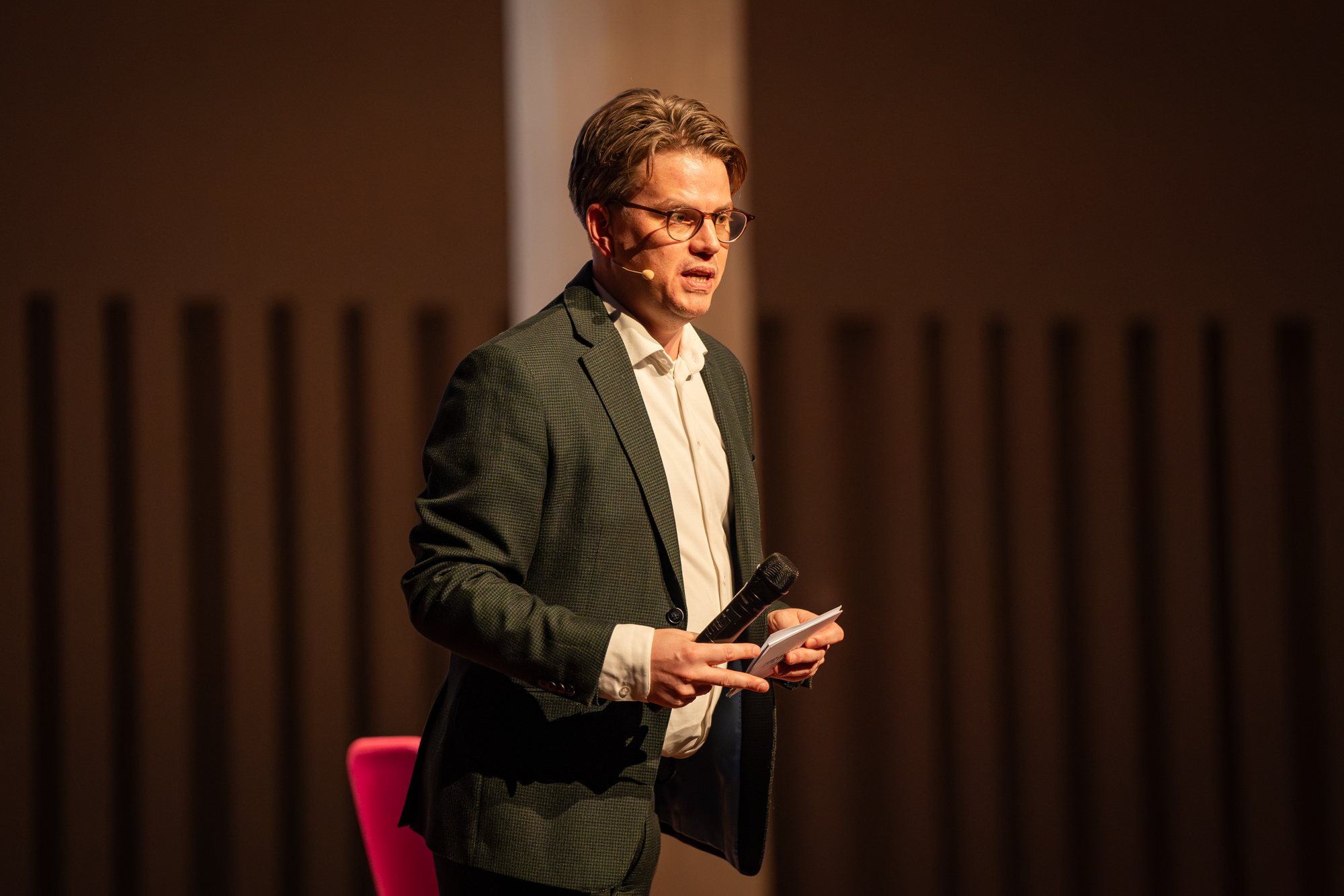Jerre Maas spreekt de zaal toe met headset-microfoon